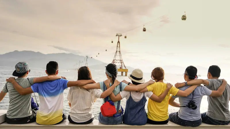 Group of friends sitting together outdoors with arms around each other